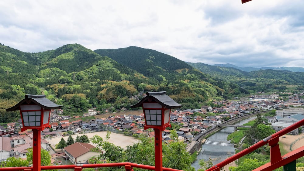 A mountainous landscape with a river, a town, and traditional red lanterns.