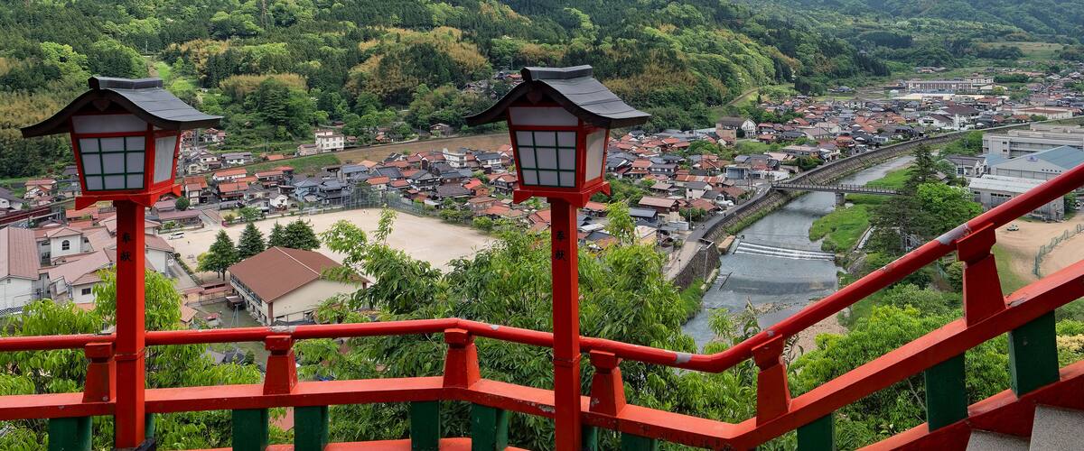A mountainous landscape with a river, a town, and traditional red lanterns.