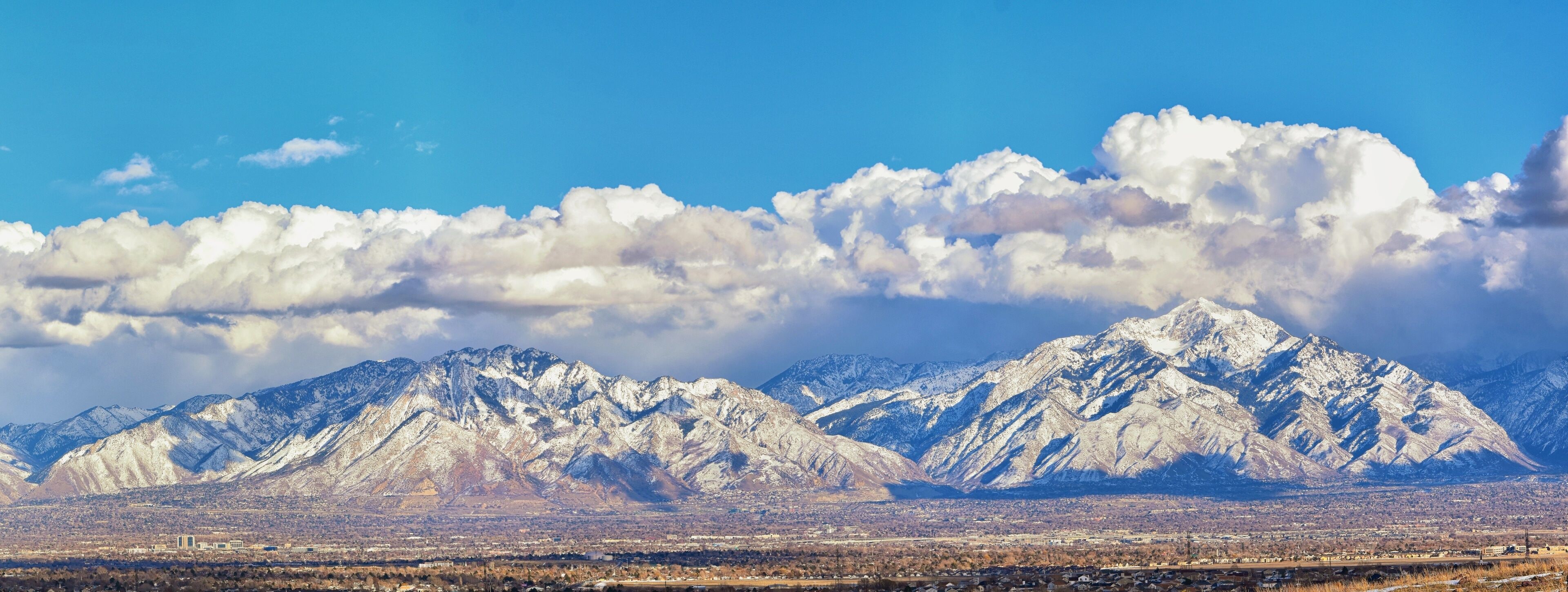 Winter Panoramic view of Snow capped Wasatch Front Rocky Mountains, Great Salt Lake Valley and Cloudscape from the Bacchus Highway. Utah, USA.