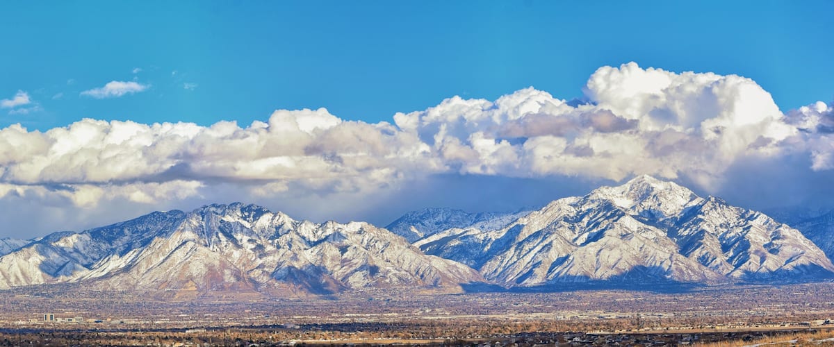 Winter Panoramic view of Snow capped Wasatch Front Rocky Mountains, Great Salt Lake Valley and Cloudscape from the Bacchus Highway. Utah, USA.
