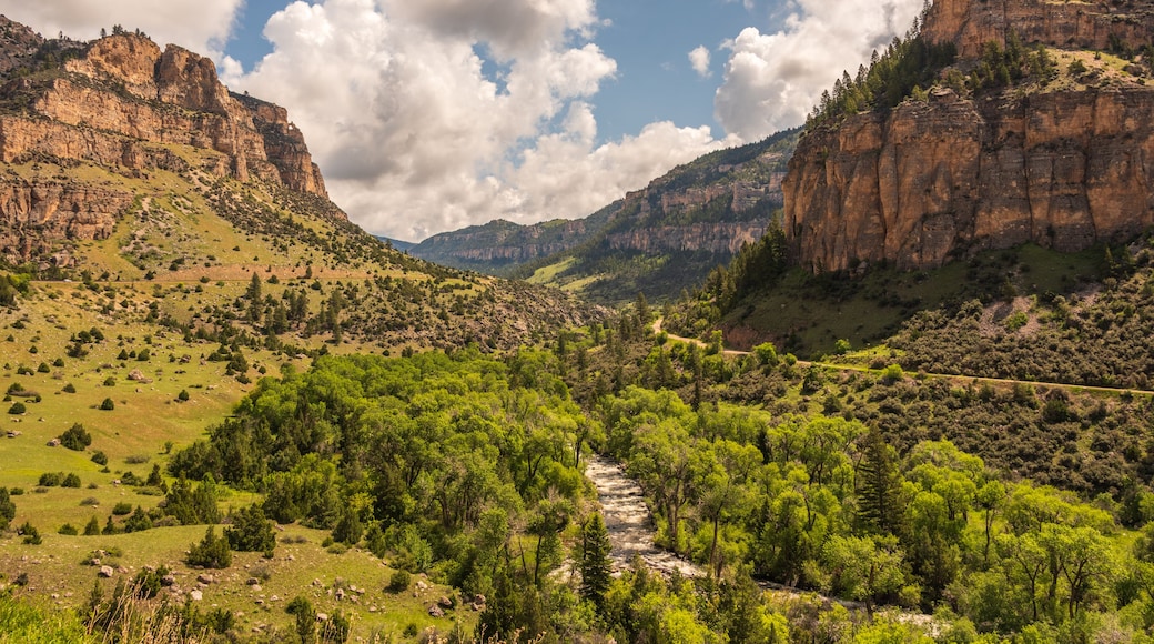 A mountainous landscape with a river flowing through a valley, surrounded by greenery and rocky cliffs.