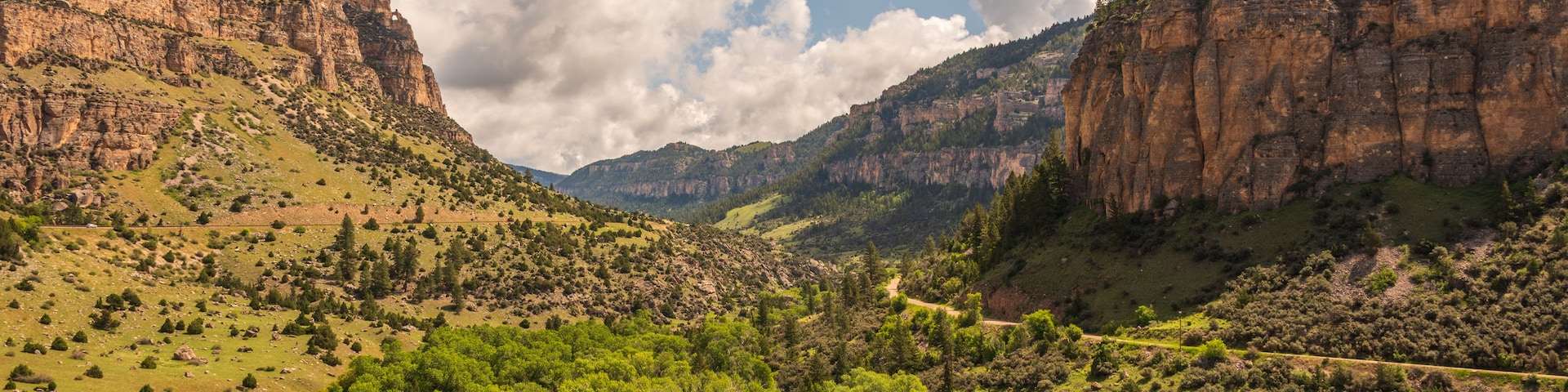 Un paisaje montañoso con un río serpenteando por un valle, rodeado de vegetación y acantilados rocosos.