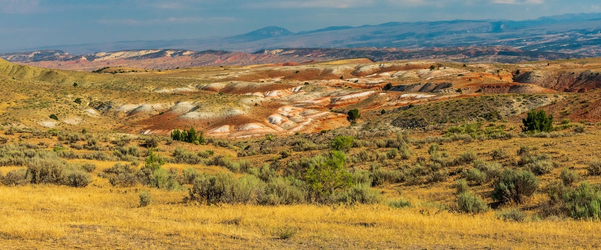 A vast desert landscape with rolling hills and sparse vegetation.