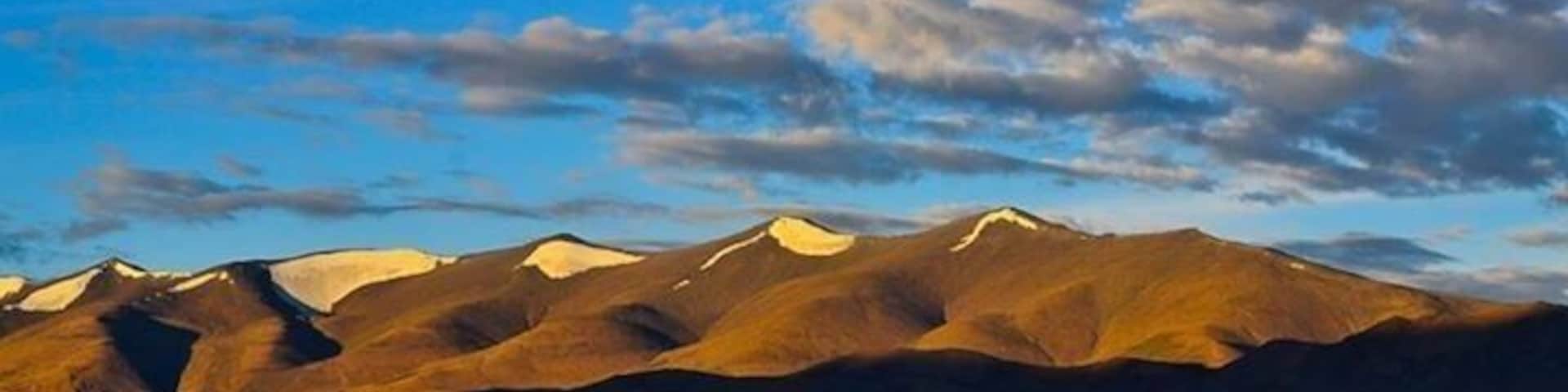Cordillera con picos nevados bajo un cielo azul con nubes dispersas.