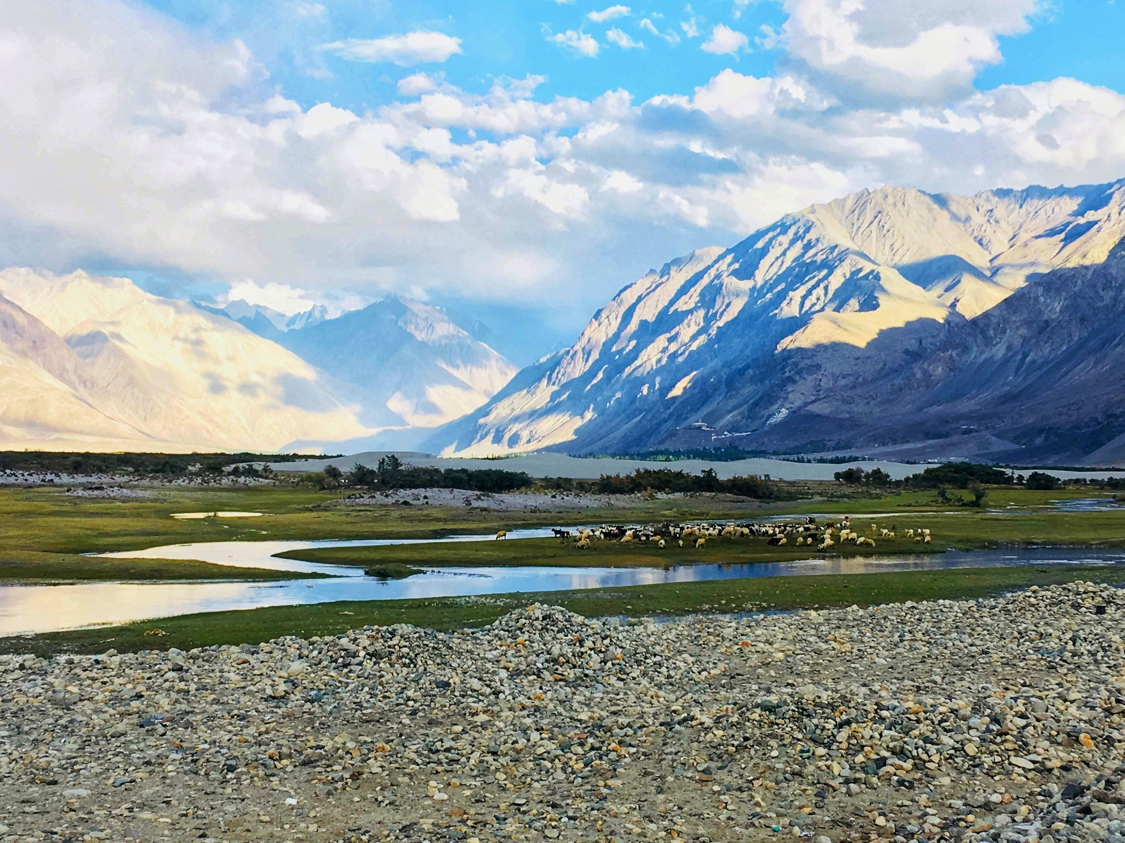 A mountainous landscape with a river and scattered rocks.