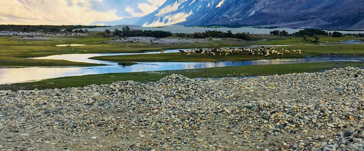 A mountainous landscape with a river and scattered rocks.
