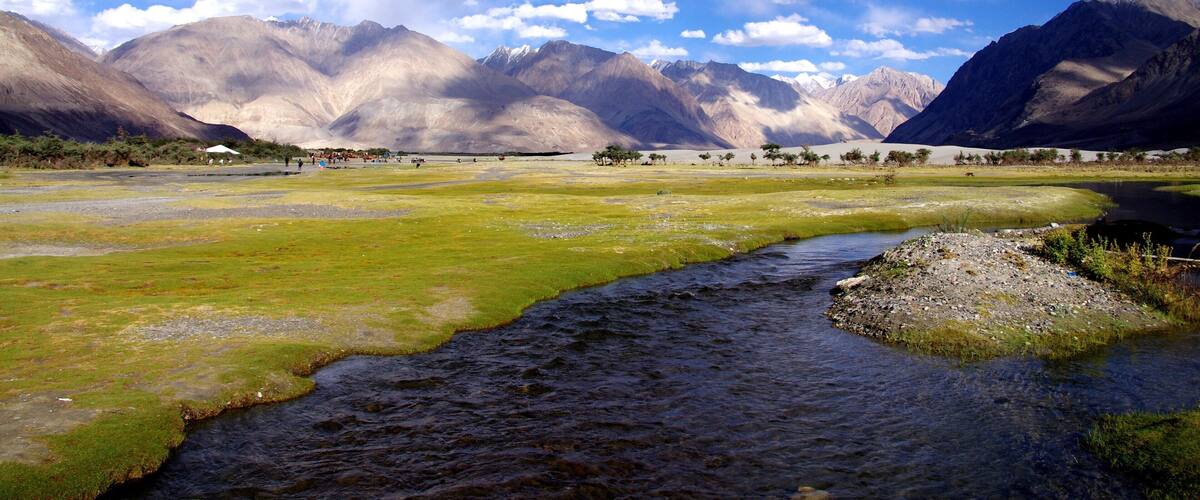A river flowing through a valley with mountains in the background.