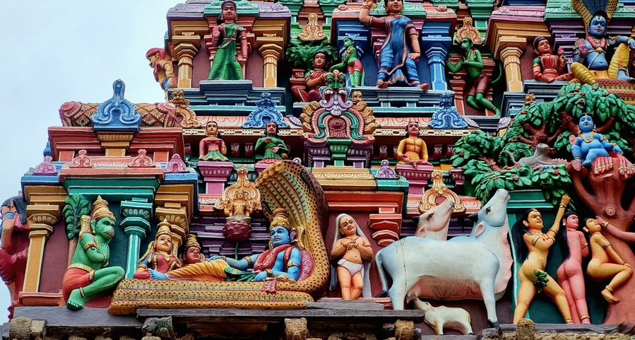 Intricately sculpted gopuram (tower) of Azhagar Temple, a historic Dravidian-style Hindu temple in Madurai, Tamil Nadu, India. The colorful carvings depict mythological figures and divine stories.