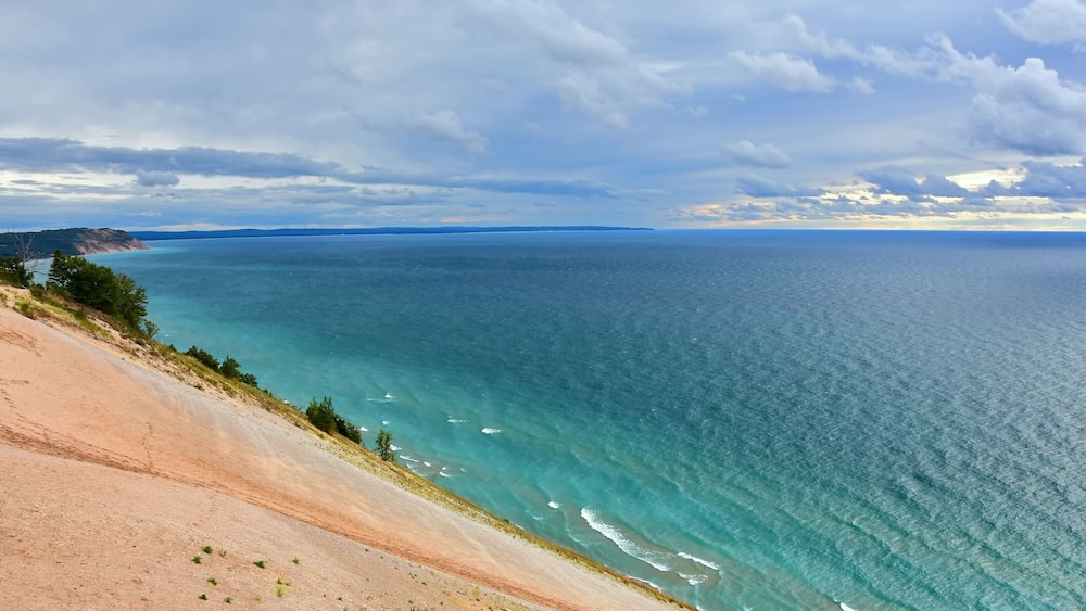 a stunning view across the turquoise-colored water of lake michigan and sand dunes from the lake michigan overlook in sleeping bear dunes national lakeshore in the lower peninsula of michigan