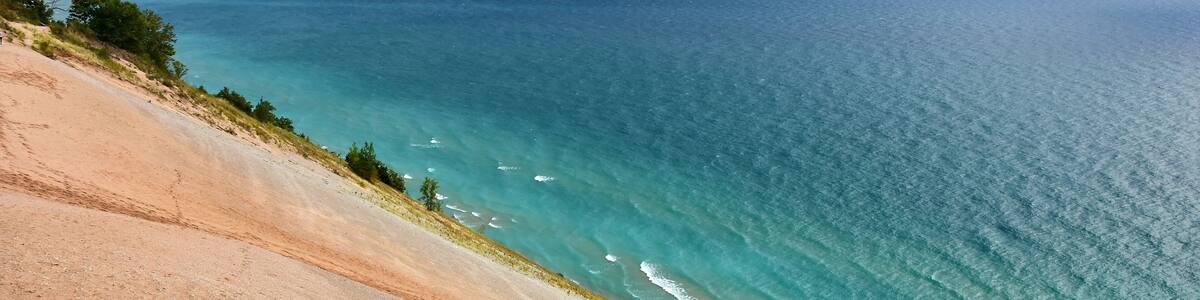a stunning view across the turquoise-colored water of lake michigan and sand dunes from the lake michigan overlook in sleeping bear dunes national lakeshore in the lower peninsula of michigan