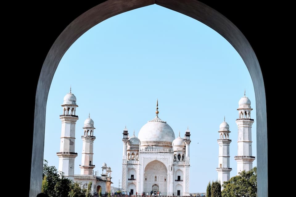 The Taj Mahal framed by an arch, with four minarets and a large central dome.