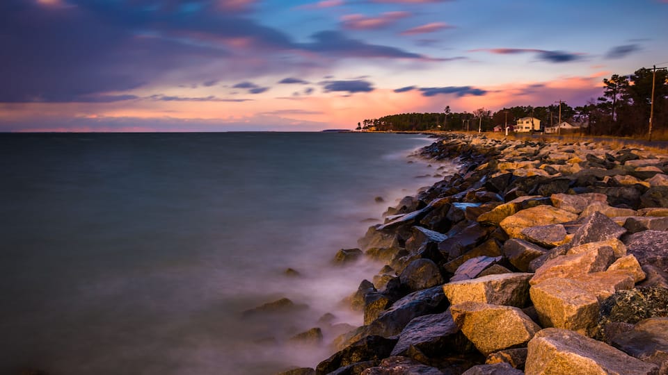 A rocky shoreline with a sunset sky.