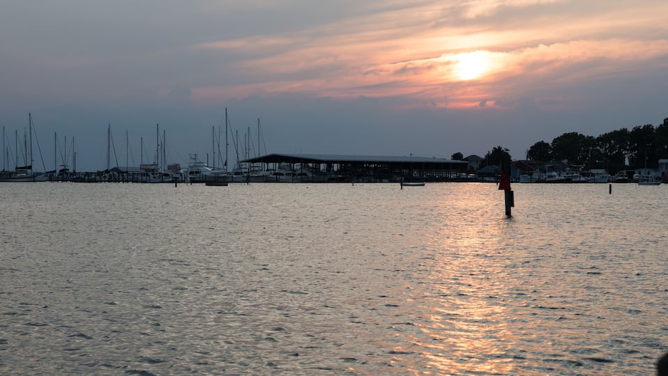 A marina with boats docked and a sunset in the background.