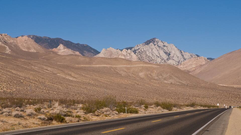 A desert road with mountains in the background.