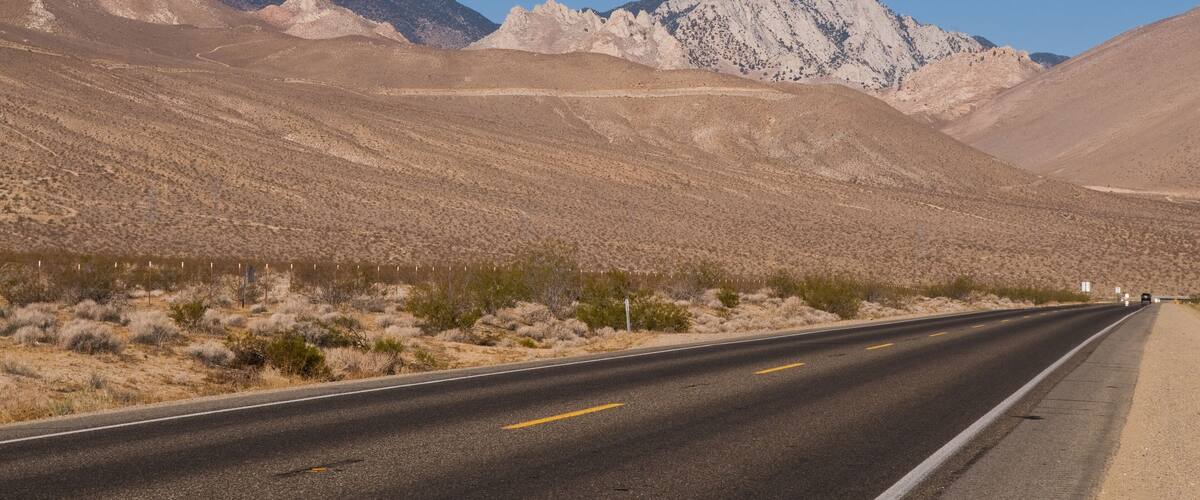 A desert road with mountains in the background.