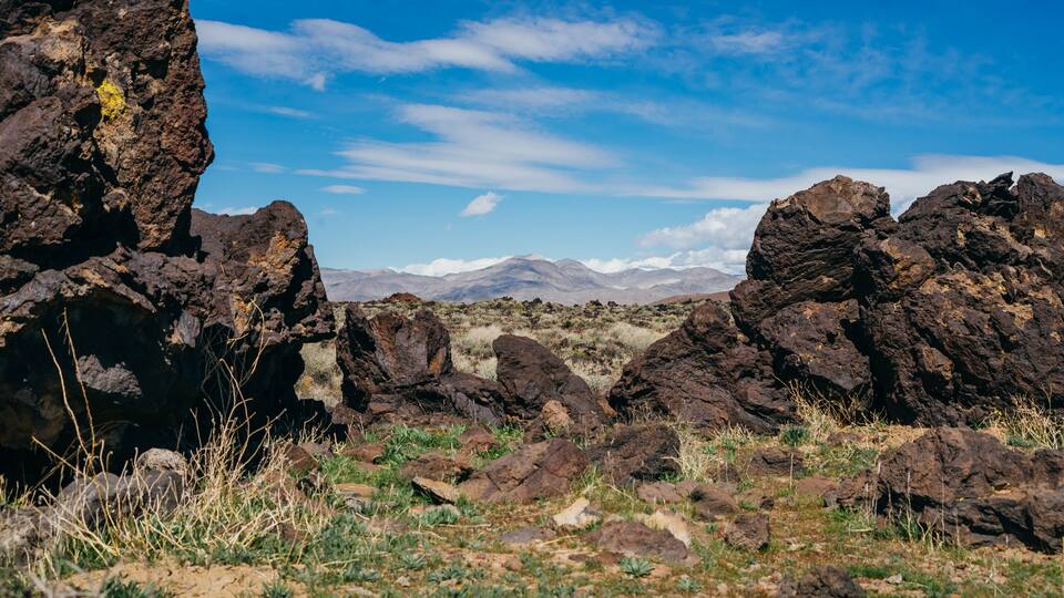 A rocky landscape with large boulders and sparse vegetation under a clear blue sky.