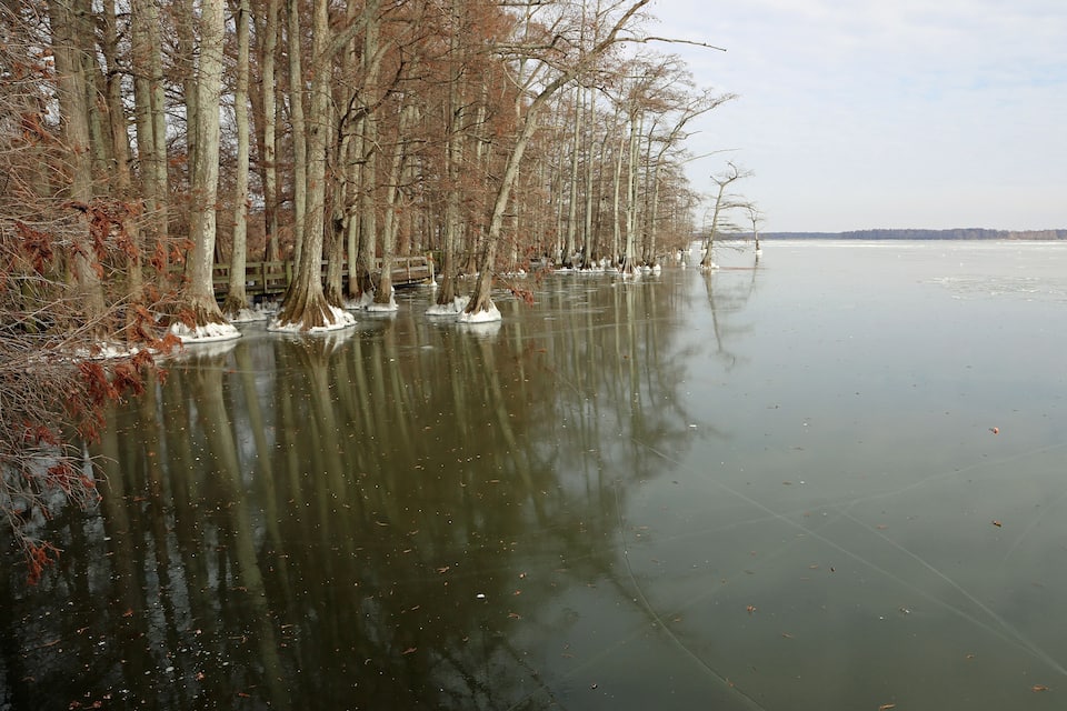 A frozen river with trees and ice sculptures along the shore.