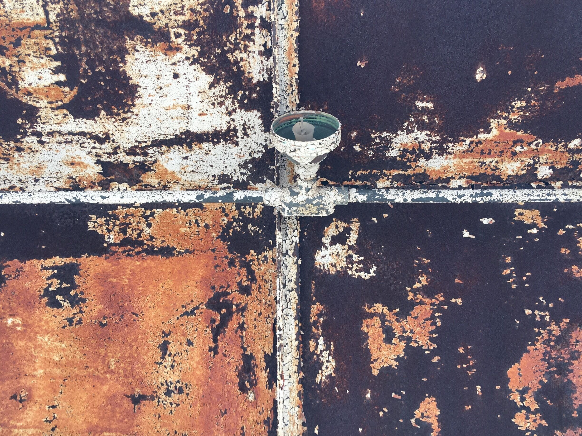 A rusted metal structure with peeling paint and a central metal cross.