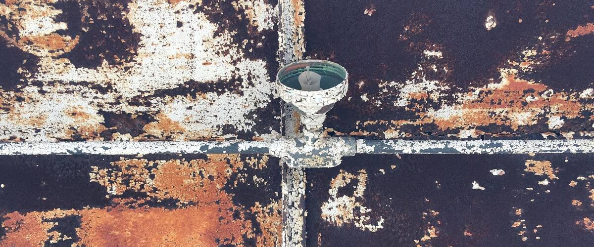 A rusted metal structure with peeling paint and a central metal cross.