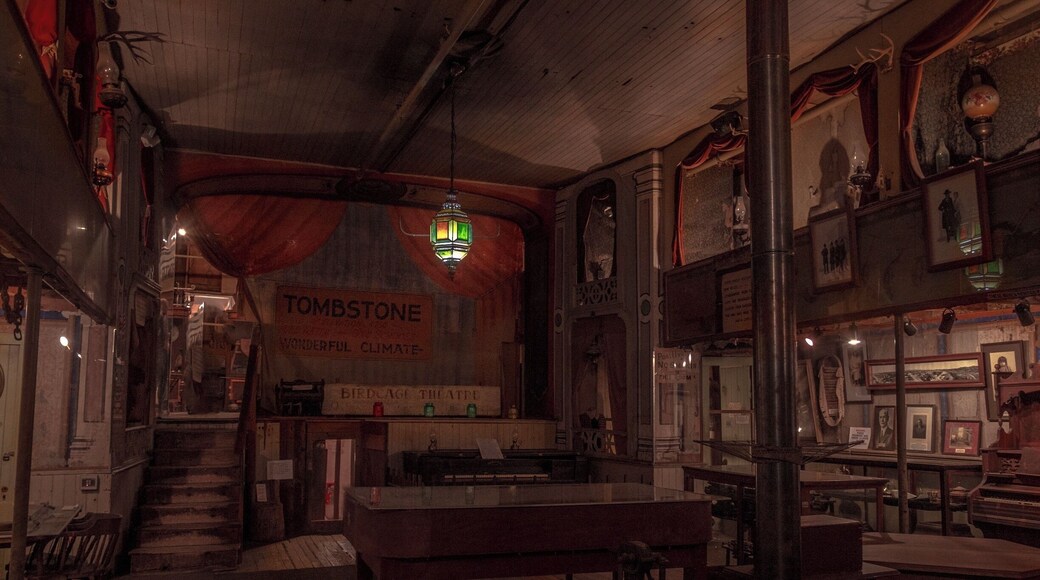 The Birdcage Theater is one of Tombstone's most authentic attractions and one of the West's most famous landmarks. Legend has it 26 people were killed in the Bird Cage during it reputed 8 years as one of the wildest and meanest places in Tombstone. Over 120 bullet holes remain in the building. The ladies of the night, plied their trade in cribs suspended from the ceiling in the building. 14 cribs lined the sides of the gambling hall, 7 on each side of the room. The ladies would pull the drapes to entertain their clients.
Within these walls once drank and played the likes of Wyatt Earp, Bat Masterson, and members of the Cowboy faction, and Doc Holliday, who dealt faro in the gambling parlor. On one occasion, while Doc was dealing, one of his hated rivals, Johnny Ringo, passed by the table. Doc then murmured, "Care to buck the tiger, Johnny? It's the gustiest game in town."
Upon hearing this, a drunken Ringo wheeled around, removed his bandana and said to Holliday,
"Care to grab to the other end of this bandanna? This is the deadliest game in town."
In those days when two men grabbed the opposite ends of a bandanna, they would then fire at each other at point-blank range, generally with both men winding up dead.
Undaunted, Doc simply stood smiling, ready to accept the challenge, but ready to use knives, rather than guns.
Curly Bill Brocius then interceded, grabbing Ringo and yelling, "Hell, Doc, he’s drunk!”
Doc, who had also been drinking, like usual, answered, "Brocius, I drink more by 10:00 a.m. than he can all day." Doc then turned and walked away.
One of its most famous distinctions was one of the longest running games of poker ever played. Seating seven players plus a dealer, the minimum buy-in was $1,000.00 and was played around the clock for, 8 years 5 months and three days.