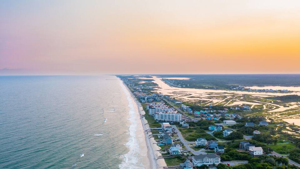 A coastal town with a beach, residential buildings, and a river.
