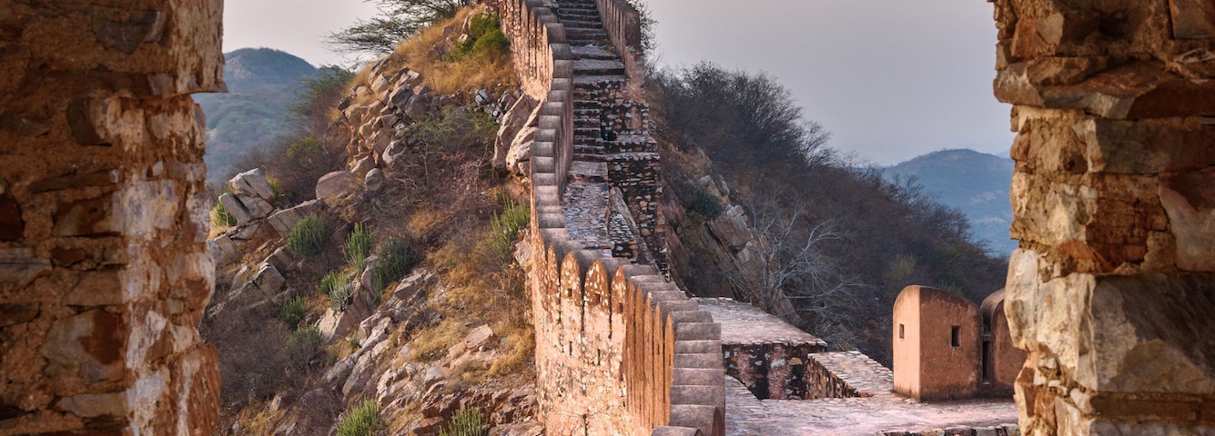 Uma antiga ponte de pedra que leva a uma torre de sino numa colina.