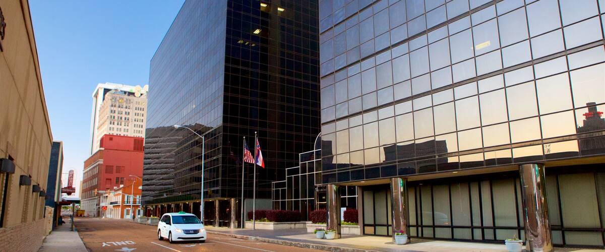 A city street with modern buildings, a white van, and American flags.