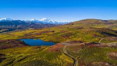 Paisagem montanhosa com um lago e uma estrada sinuosa.