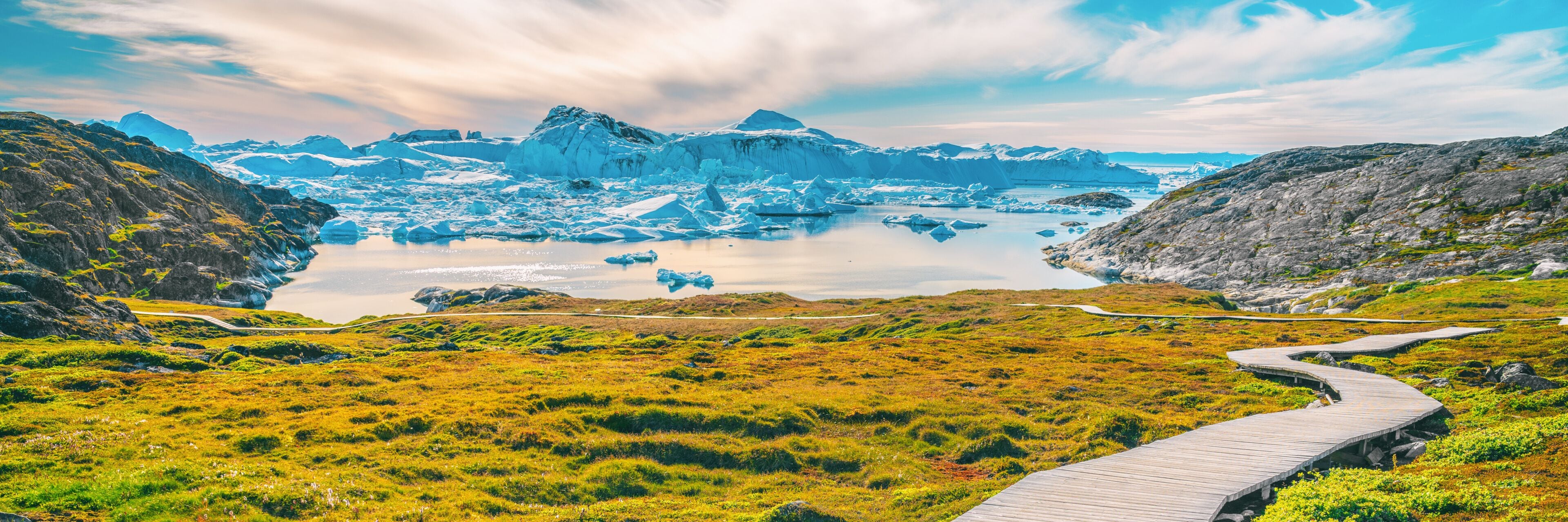 Un glaciar con icebergs, cielo despejado y un muelle de madera.