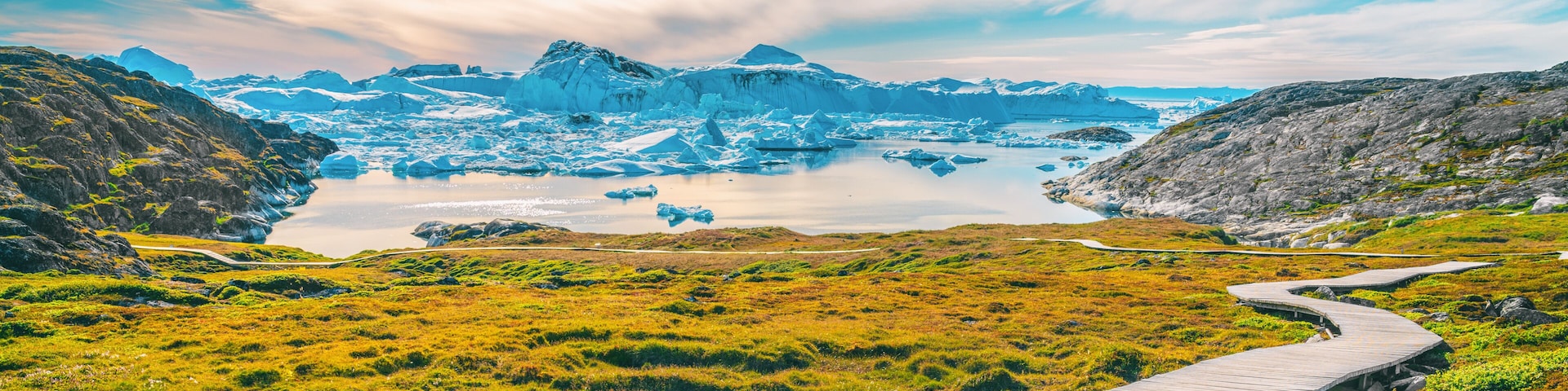 Un glaciar con icebergs, cielo despejado y un muelle de madera.