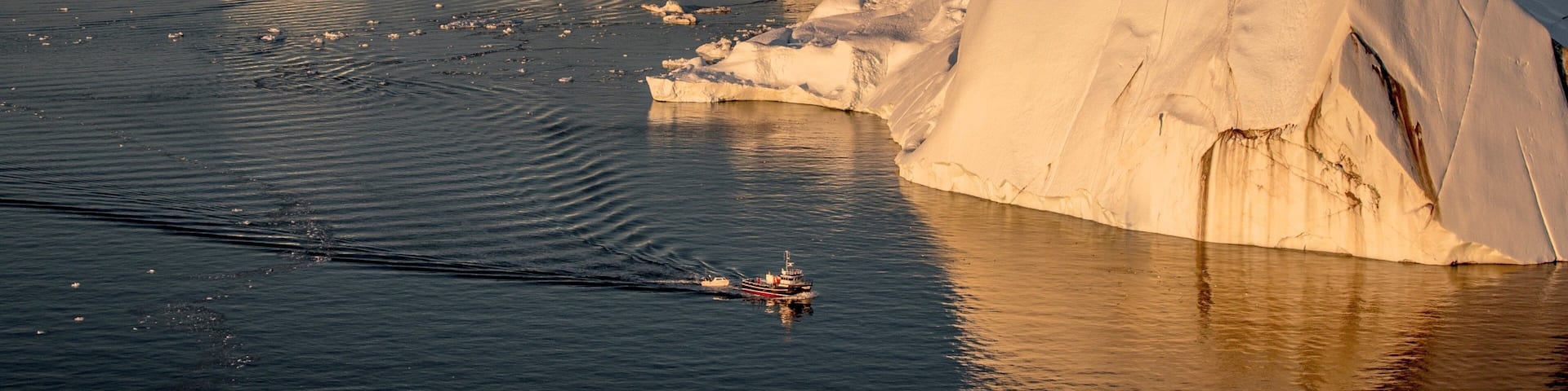 Ilulissat featuring snow, rugged coastline and boating