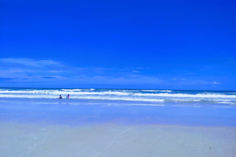 Una playa con cielo azul despejado y olas del océano.