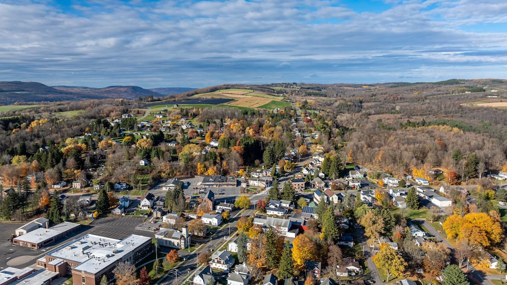 A town surrounded by autumn-colored trees and rolling hills.