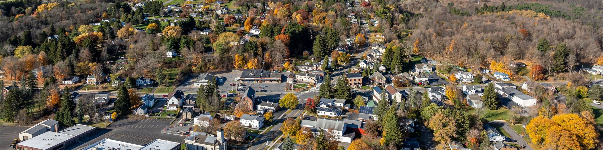 A town surrounded by autumn-colored trees and rolling hills.