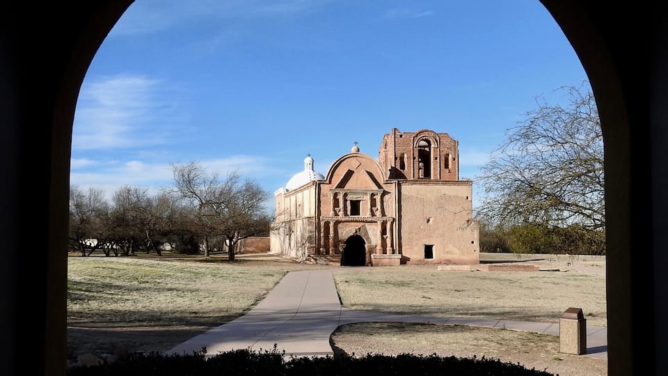 An arched view of a historical building with a dome and bell tower.