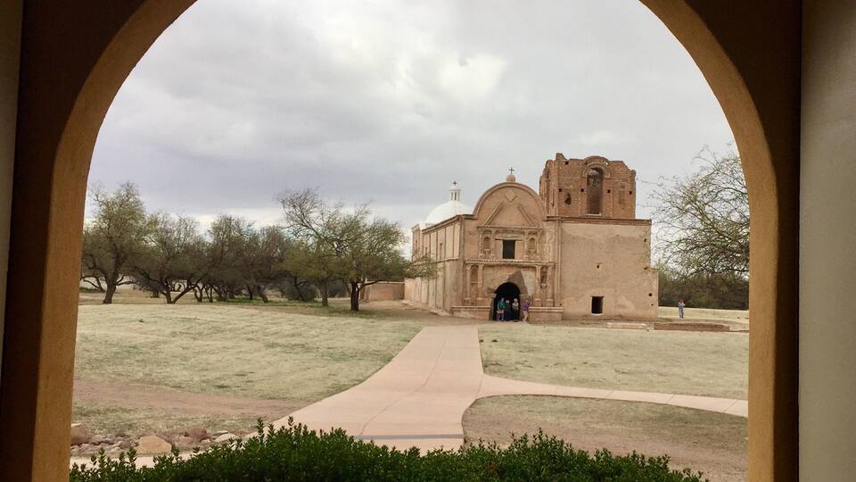 An arched window framing a historic building with a dome and bell tower.
