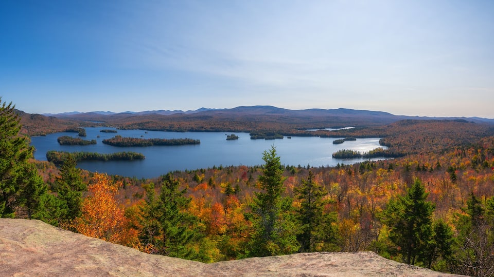 A mountainous landscape with a lake surrounded by autumn-colored trees.