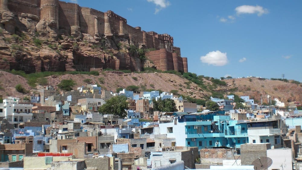 A historic fort overlooking a densely packed town with blue buildings.