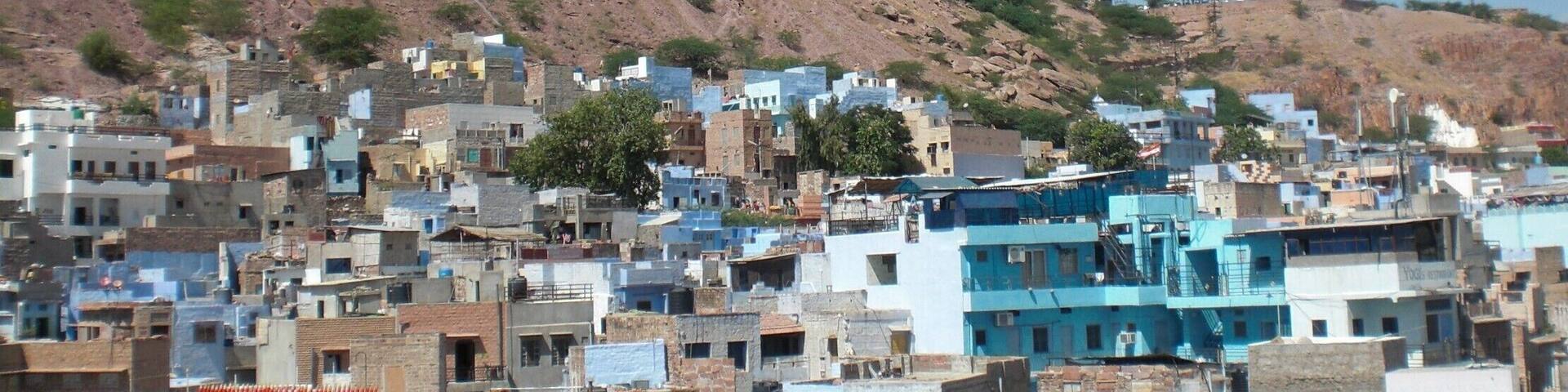 A historic fort overlooking a densely packed town with blue buildings.
