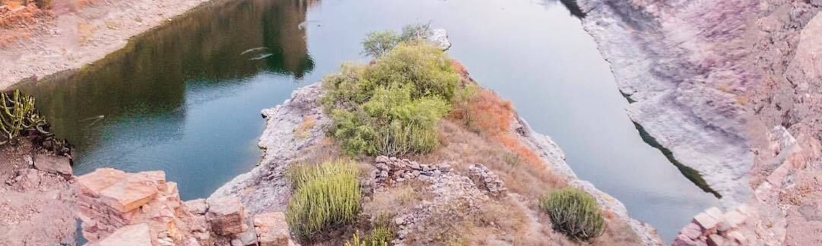 You probably haven’t seen many shots of Jodhpur that look like this.
That’s because we always go the extra mile to bring you guys unique, original content and images that you’ll rarely find elsewhere. 
Twobirdsbreakingfree is about innovation, creativity, pushing your edges and blazing your own trail as a traveller.
We like guidebooks but we don’t follow them slavishly. 
To get our exclusive images we often have to gain access to restricted or off-limits areas, sometimes even risking our safety.
You’ll often see us leaning backwards over the edge of a cliff or a high wall to get that perfect camera angle. 
To get this shot of Ranisar Talab lake behind the majestic Mehrangarh fort of the blue city of Jodhpur in Rajasthan, India, we had to step outside of what would be most people’s comfort zones. 
We had to traverse a wild, rocky desert landscape, navigate a steep incline, pass through a tiny doorway in an ancient crumbling fort wall, and then clamber up a steep slope of rubble and loose rocks to get up on top of that very same fort wall. 
Once at the very top of the wall looking out over the lake, I had to back up to the very edge of the wall and avoid falling to my death to the ground over 30 metres below, just to get that perfect shot. 
This was an off-limits part of the Mehrangarh fort complex where the vast majority of tourists almost never venture!
Epic shots often have epic stories behind them!  We wanted to bring this issue to light, as many people don’t understand that if you want to take extraordinary travel photos, you sometimes have to be willing to do extraordinary things and step far outside of your comfort zone. 
And what about you? Do you go the extra mile for your travel photos or do you prefer the more passive approach, waiting until an amazing image finds you instead? Do you go chasing light, or wait for the light to come to you?