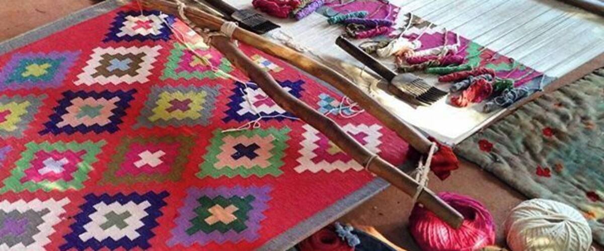 A traditional loom with colorful fabrics and yarns.