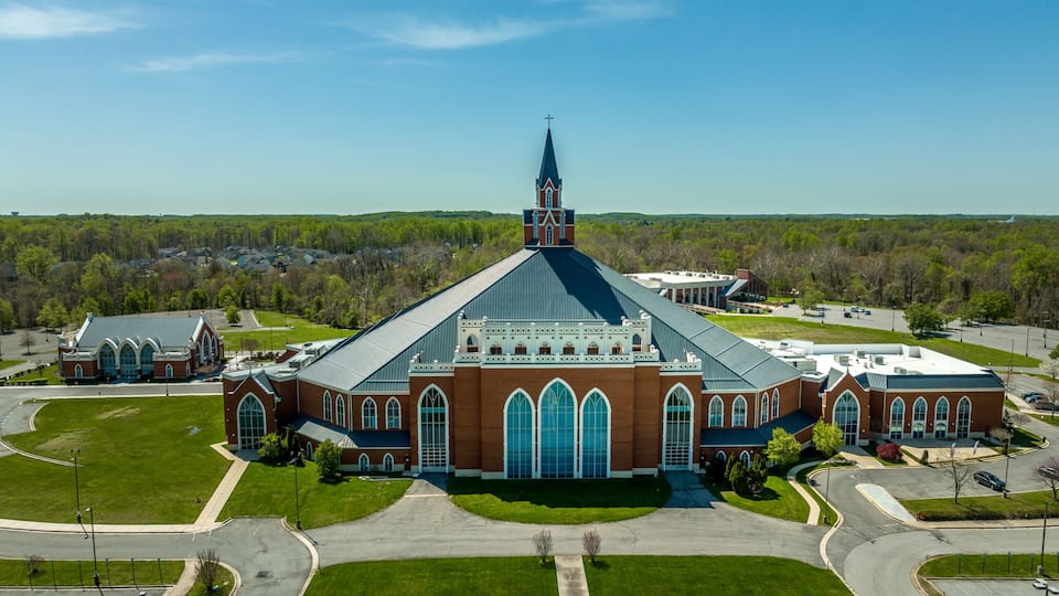 A large church with a prominent steeple, surrounded by green lawns and a parking lot.
