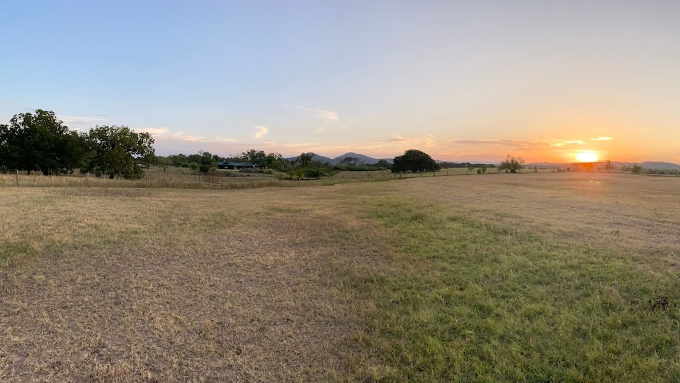 A rural landscape with a dirt path leading to a sunset.