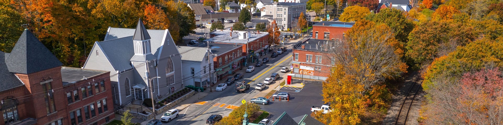 A town with autumn foliage, a church, and a train track.