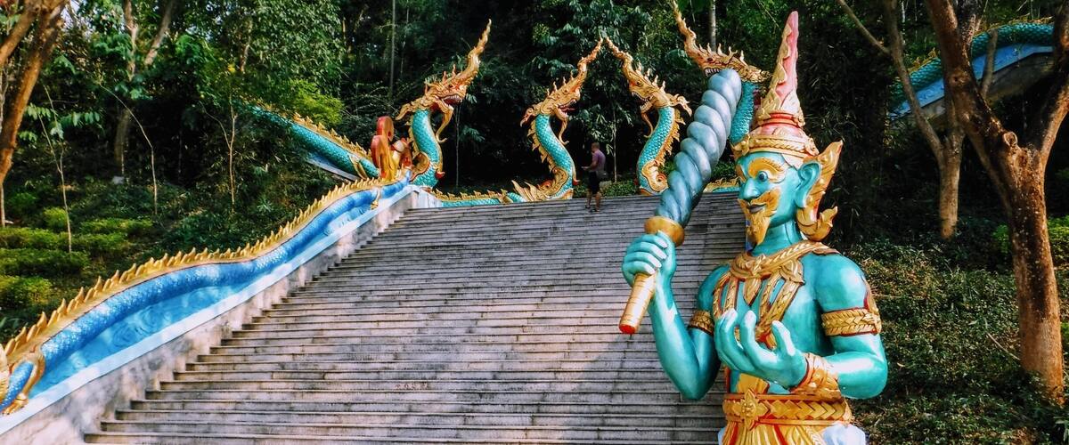 A temple staircase with a statue of a blue deity holding a staff.