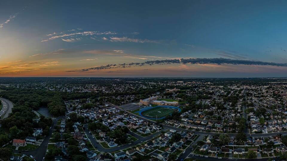 An aerial view of a city at sunset with a large cloud formation over the horizon.