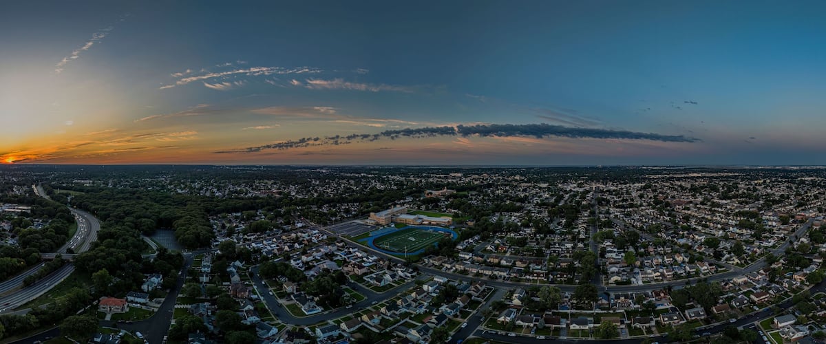 An aerial view of a city at sunset with a large cloud formation over the horizon.