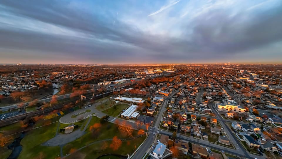 An aerial view of a cityscape with a river, a large industrial area, and a dense residential neighborhood.