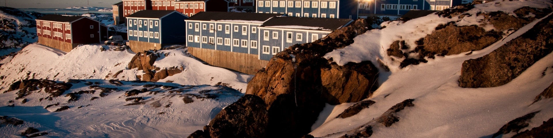 A snowy landscape with buildings and mountains.