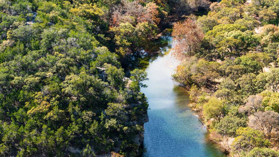 A river winding through a dense forest with rocky outcrops.